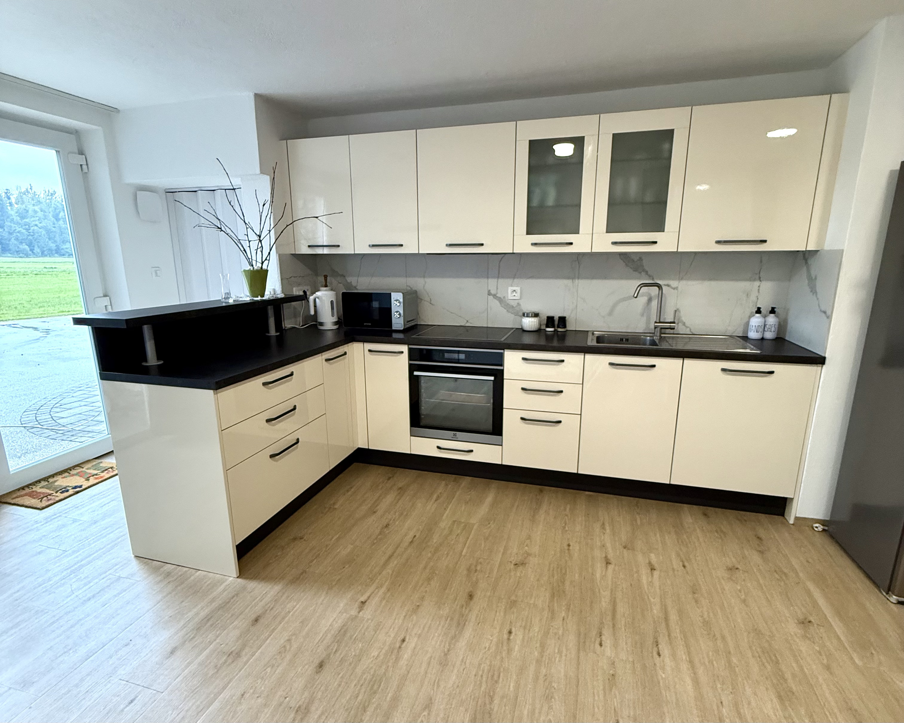 Fully equipped kitchen with marble backsplash and cream gloss cabinets
