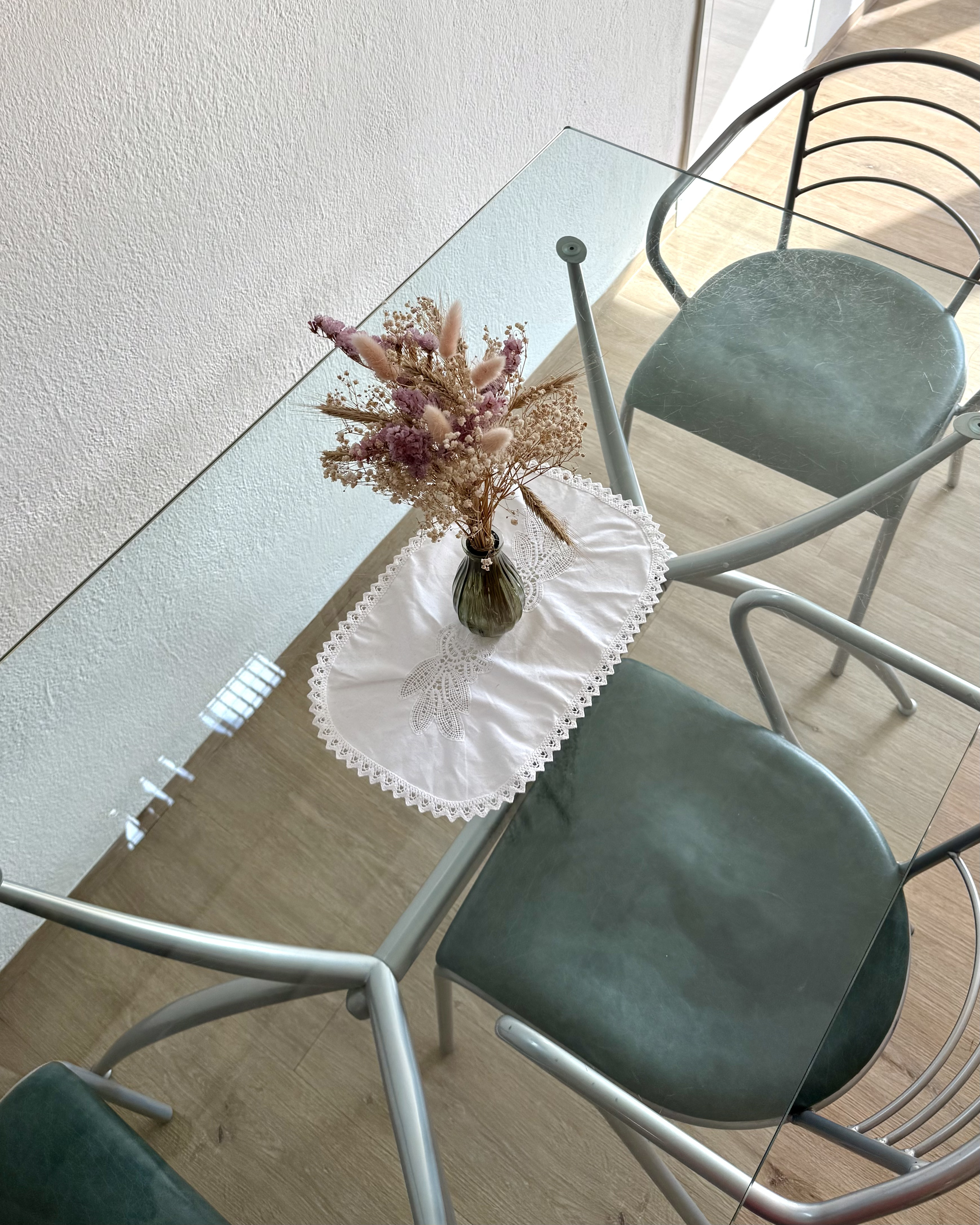 Glass dining table with dried flower arrangement viewed from above
